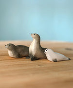 Two Bumbu Toys harp seal and a pup handmade wooden toy figures placed on a wooden surface.