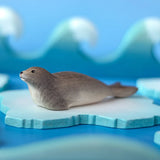 Bumbu harp seal handmade wooden toy figure placed on a on ice pieces in a small world play scene.