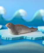Bumbu harp seal handmade wooden toy figure placed on a on ice pieces in a small world play scene.