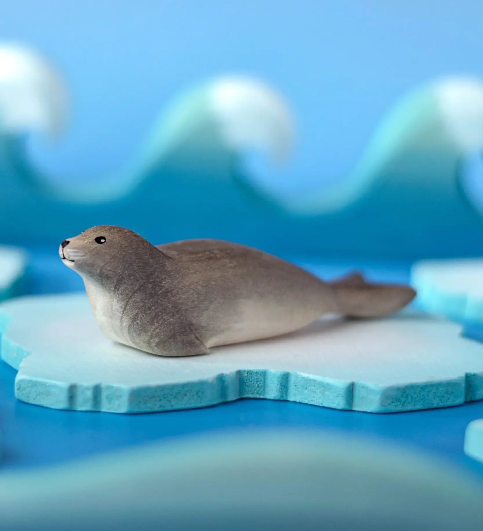 Bumbu harp seal handmade wooden toy figure placed on a on ice pieces in a small world play scene.