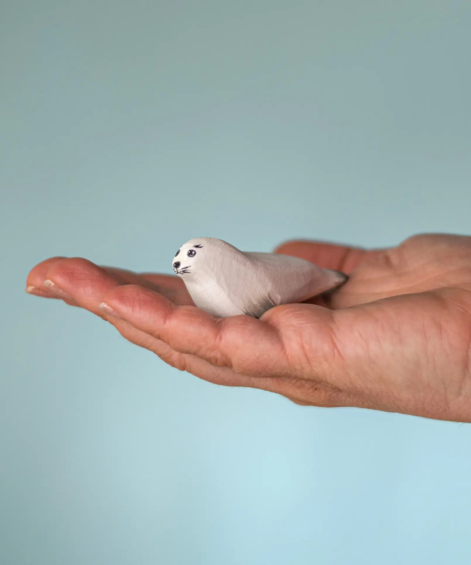 Bumbu Toys harp seal pup handmade wooden toy figure in an adult's hand.