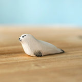 Bumbu Toys harp seal pup handmade wooden toy figure placed on a wooden surface.