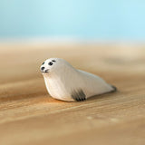 Bumbu Toys harp seal pup handmade wooden toy figure placed on a wooden surface.