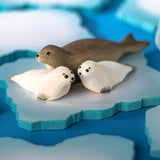 Two Bumbu Toys harp seal pups handmade wooden toy figures placed on an ice flow with an adult harp seal.
