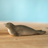 Bumbu harp seal handmade wooden toy figure placed on a wooden surface.