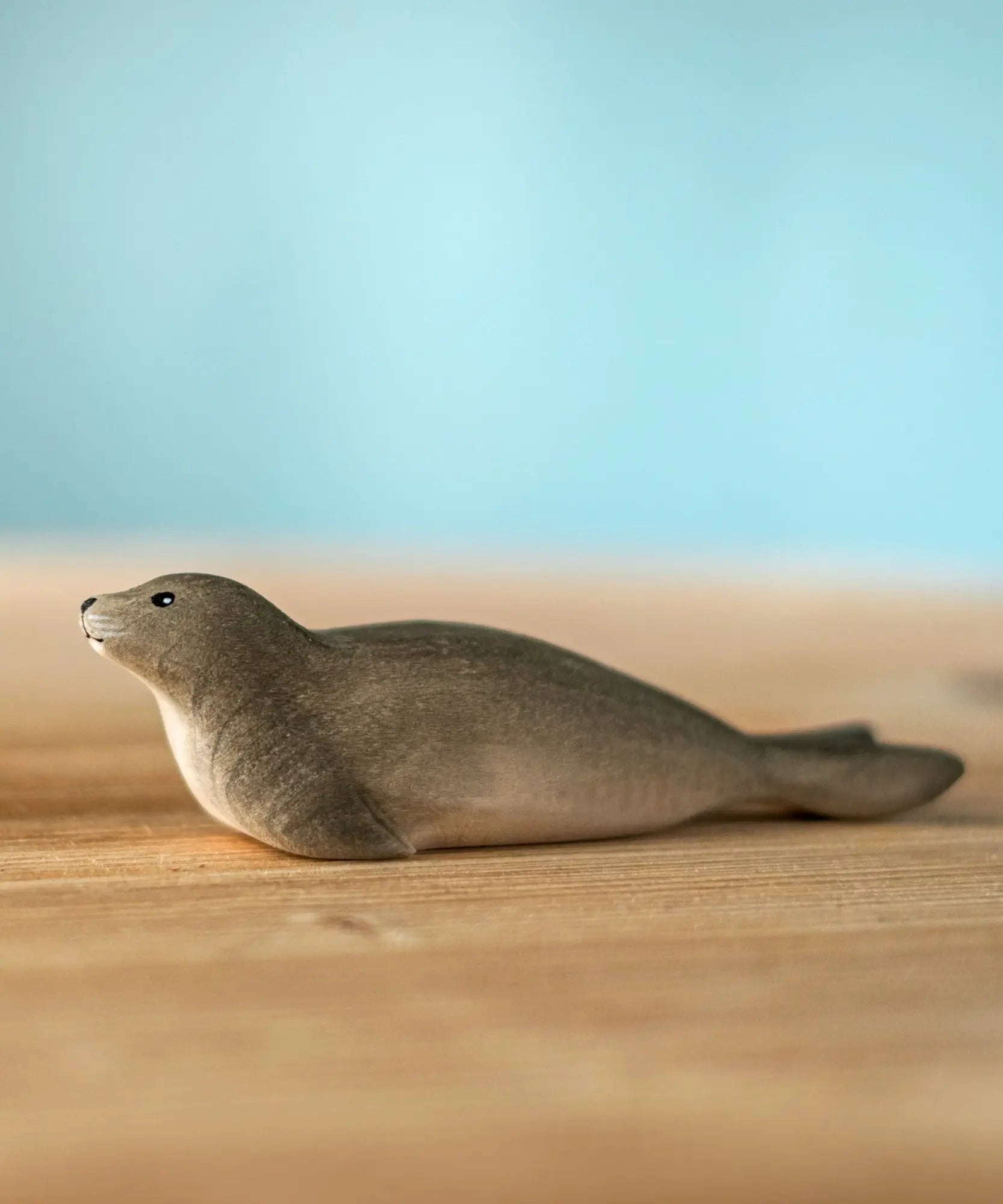Bumbu harp seal handmade wooden toy figure placed on a wooden surface.