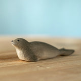 Bumbu harp seal handmade wooden toy figure placed on a wooden surface.