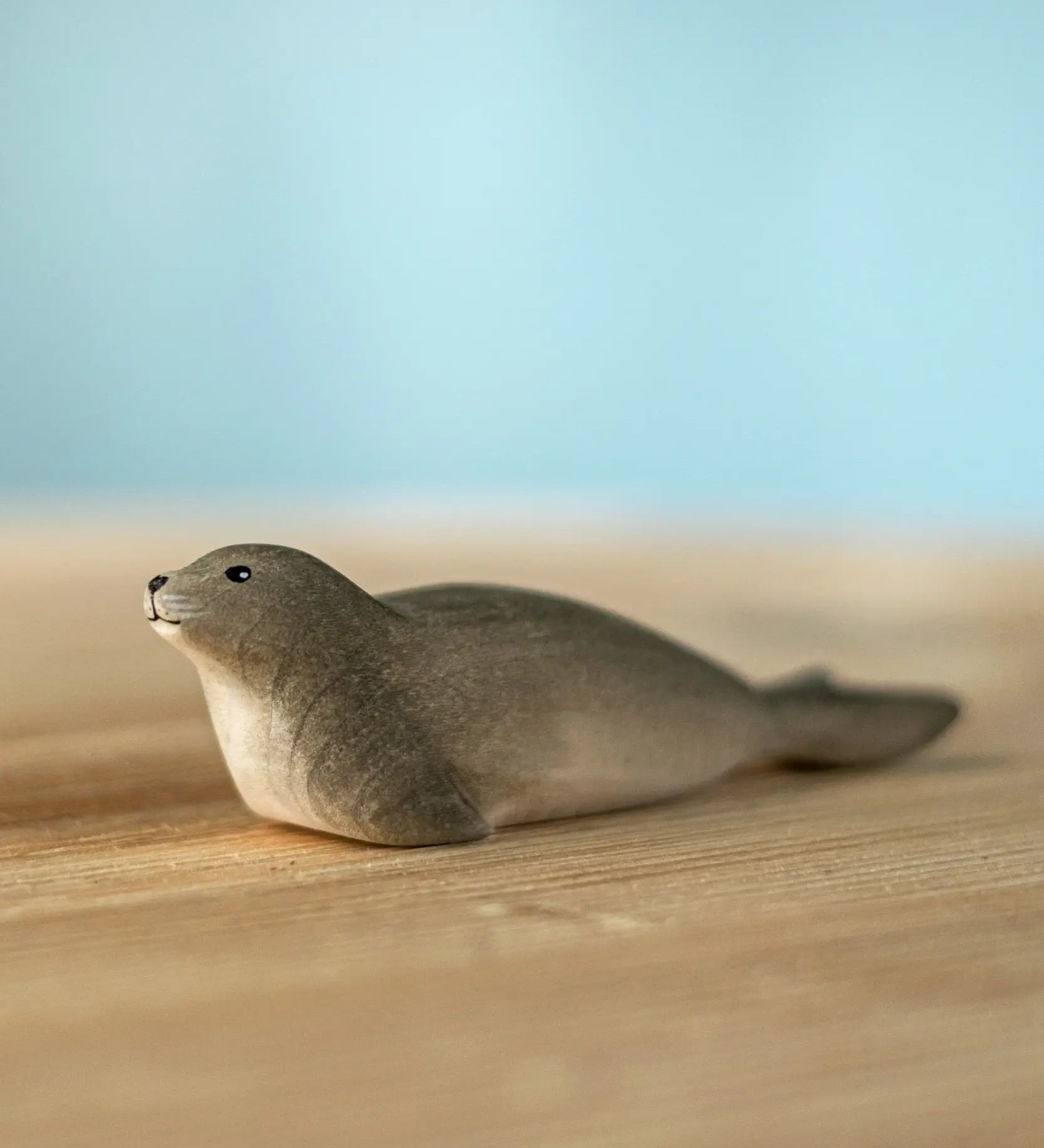 Bumbu harp seal handmade wooden toy figure placed on a wooden surface.