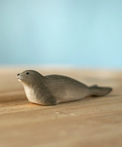 Bumbu harp seal handmade wooden toy figure placed on a wooden surface.