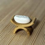 Bumbu Handmade Wooden baby Jesus in a white painted blanket and crib figure on a wooden table.