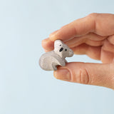 A Bumbu Toys handmade wooden Koala Cub figure in an adult's hand. 