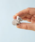 A Bumbu Toys handmade wooden Koala Cub figure in an adult's hand. 