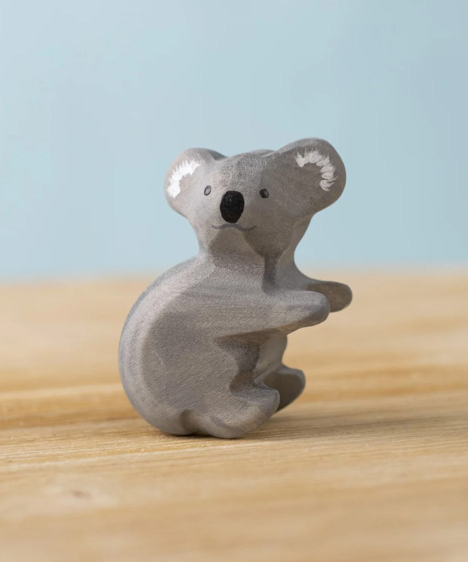 Bumbu Toys handmade wooden Koala figure placed on a wooden surface. 