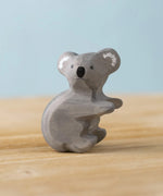 Bumbu Toys handmade wooden Koala figure placed on a wooden surface. 