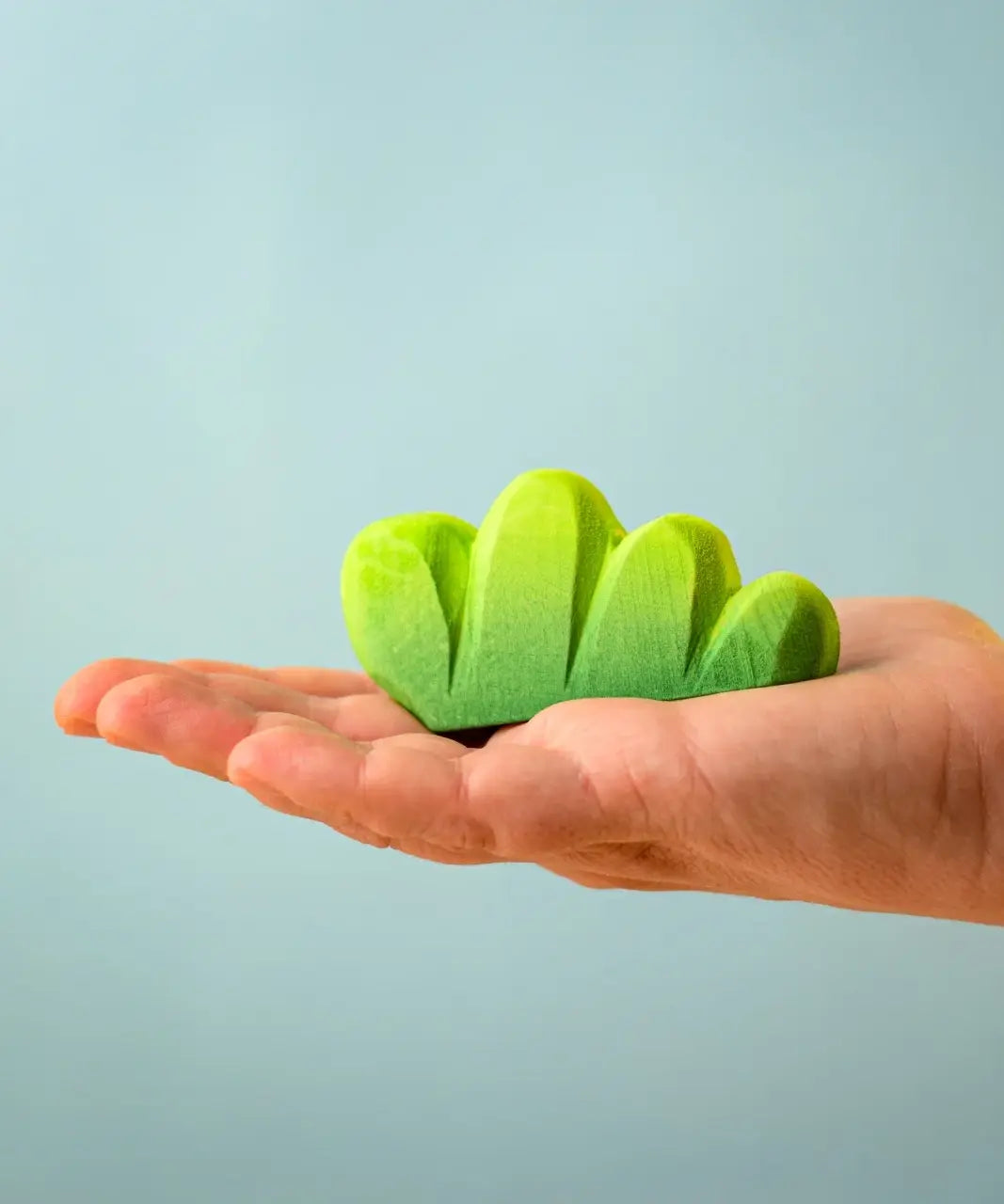 Bumbu Toys lake bush wooden toy scenery piece in an adult's hand.