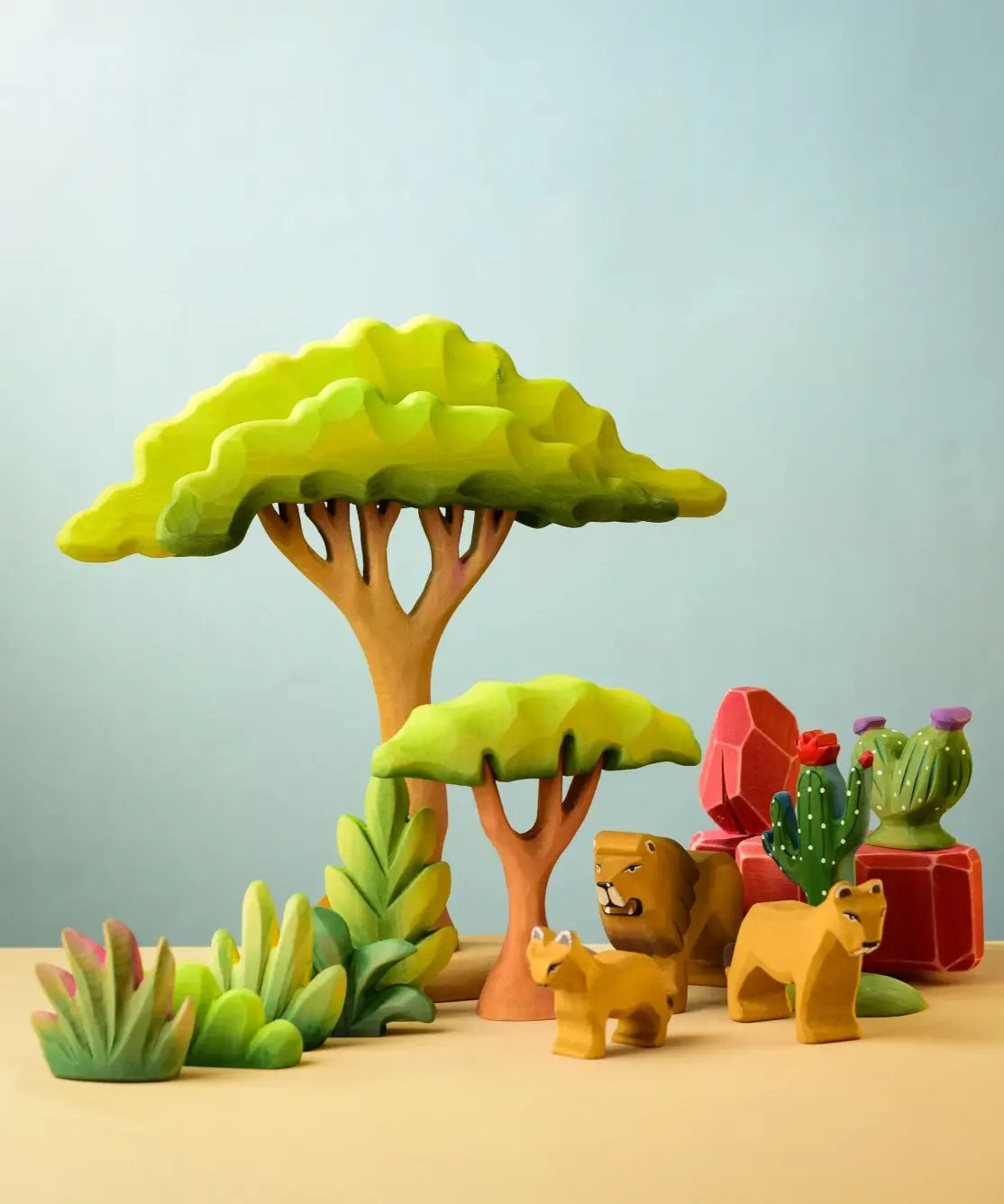 Bumbu Toys lake bush wooden toy scenery piece placed in a small world play scene with lions, rocks, cacti and other bushes and trees.