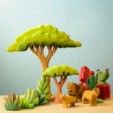 Bumbu Toys lake bush wooden toy scenery piece placed in a small world play scene with lions, rocks, cacti and other bushes and trees.