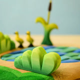 Bumbu Toys lake bush wooden toy scenery piece placed in a small world play scene with a lake and ducklings in the background.