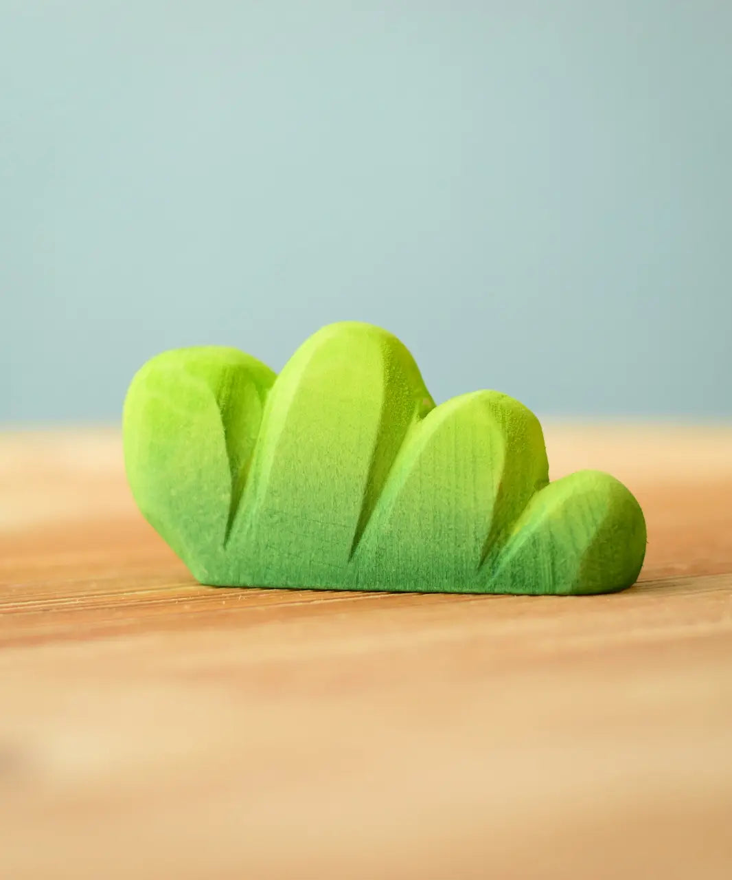 Bumbu Toys lake bush wooden toy scenery piece placed on a wooden surface. 