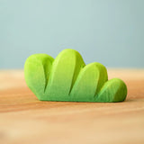 Bumbu Toys lake bush wooden toy scenery piece placed on a wooden surface. 