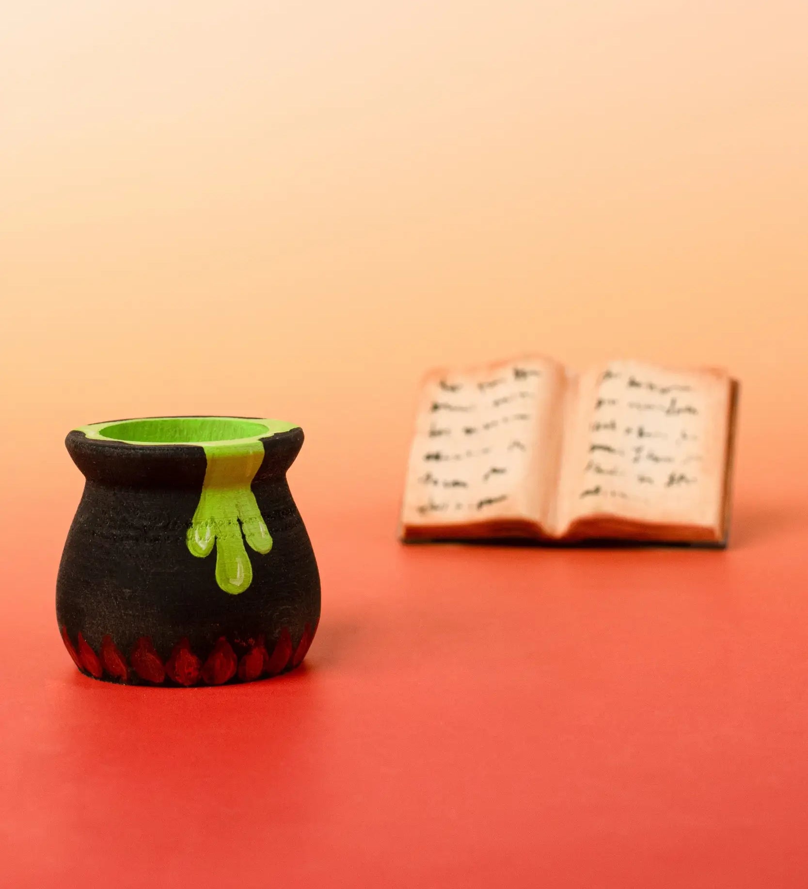 Bumbu handcrafted wooden black magic cauldron decorative figure in front of a spell book