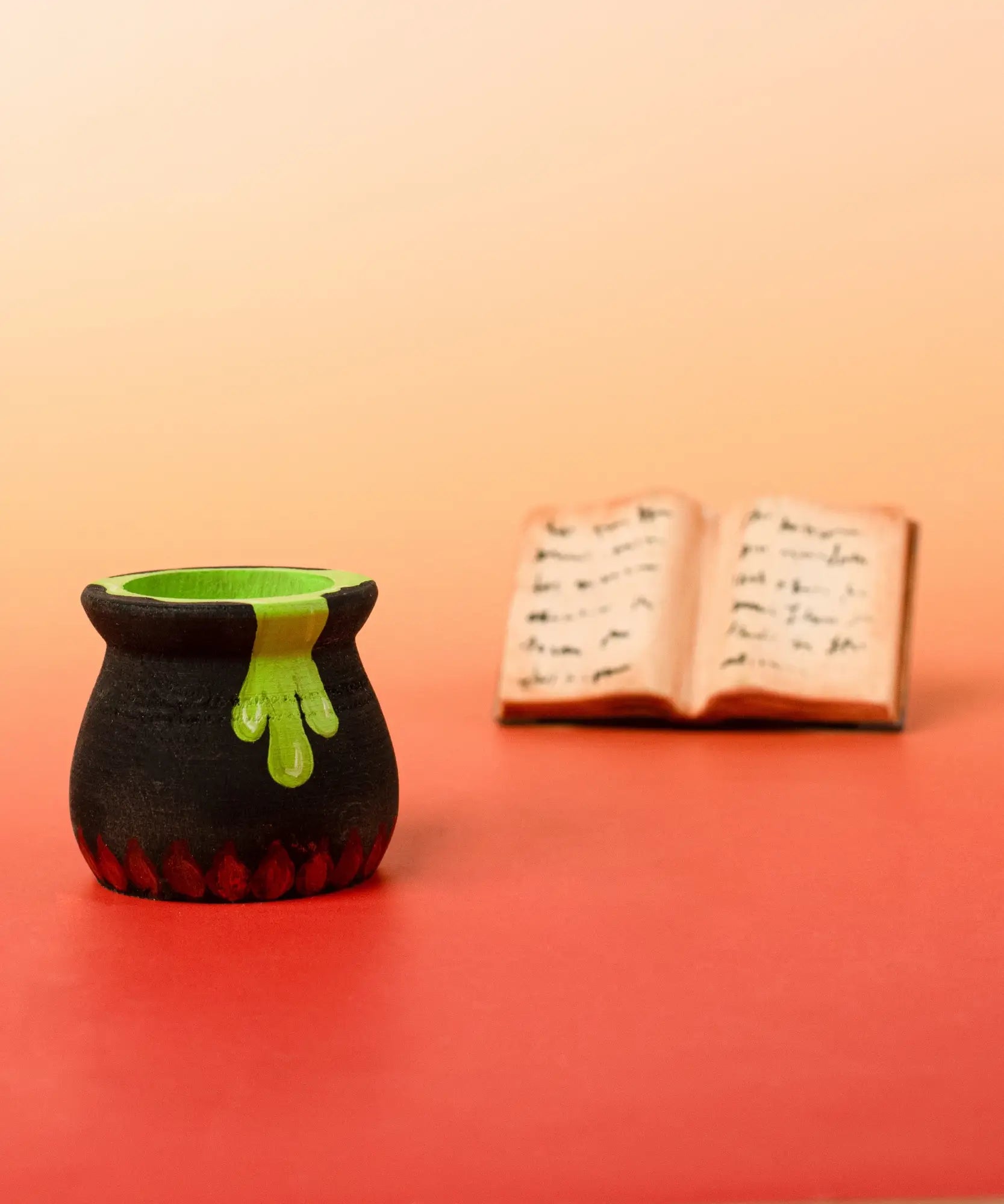 Bumbu handcrafted wooden black magic cauldron decorative figure in front of a spell book