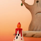 Bumbu handcrafted wooden magic red candle with a friendly face in front of a spooky tree figure