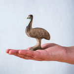 A hand holding the Bumbu wooden male emu 