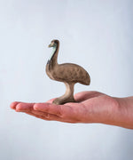 A hand holding the Bumbu wooden male emu 