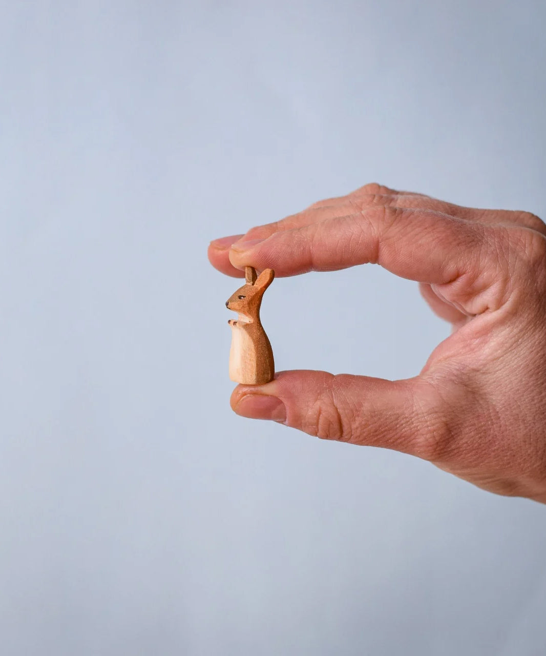 The little joey from the Bumbu Toys Mama Kangaroo & Joey figures set up shown in an adult's hand to show scale.