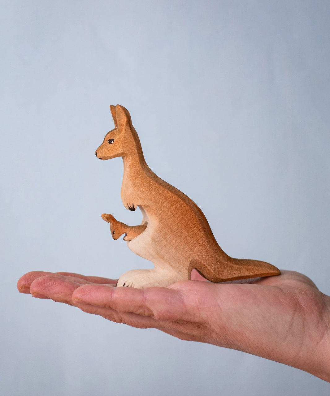 Bumbu Toys Mama Kangaroo & Joey figures set up shown in an adult's hand to show scale.