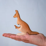 Bumbu Toys Mama Kangaroo & Joey figures set up shown in an adult's hand to show scale.