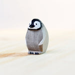 Bumbu handmade eco-friendly miniature wooden penguin chick toy figure stood on a wooden work top in front of a white background
