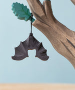 Bumbu handmade and hand painted wooden bat figure available at Babipur with its wings spread out. Features a small hole with a thread looping through for the bat to hang off a tree