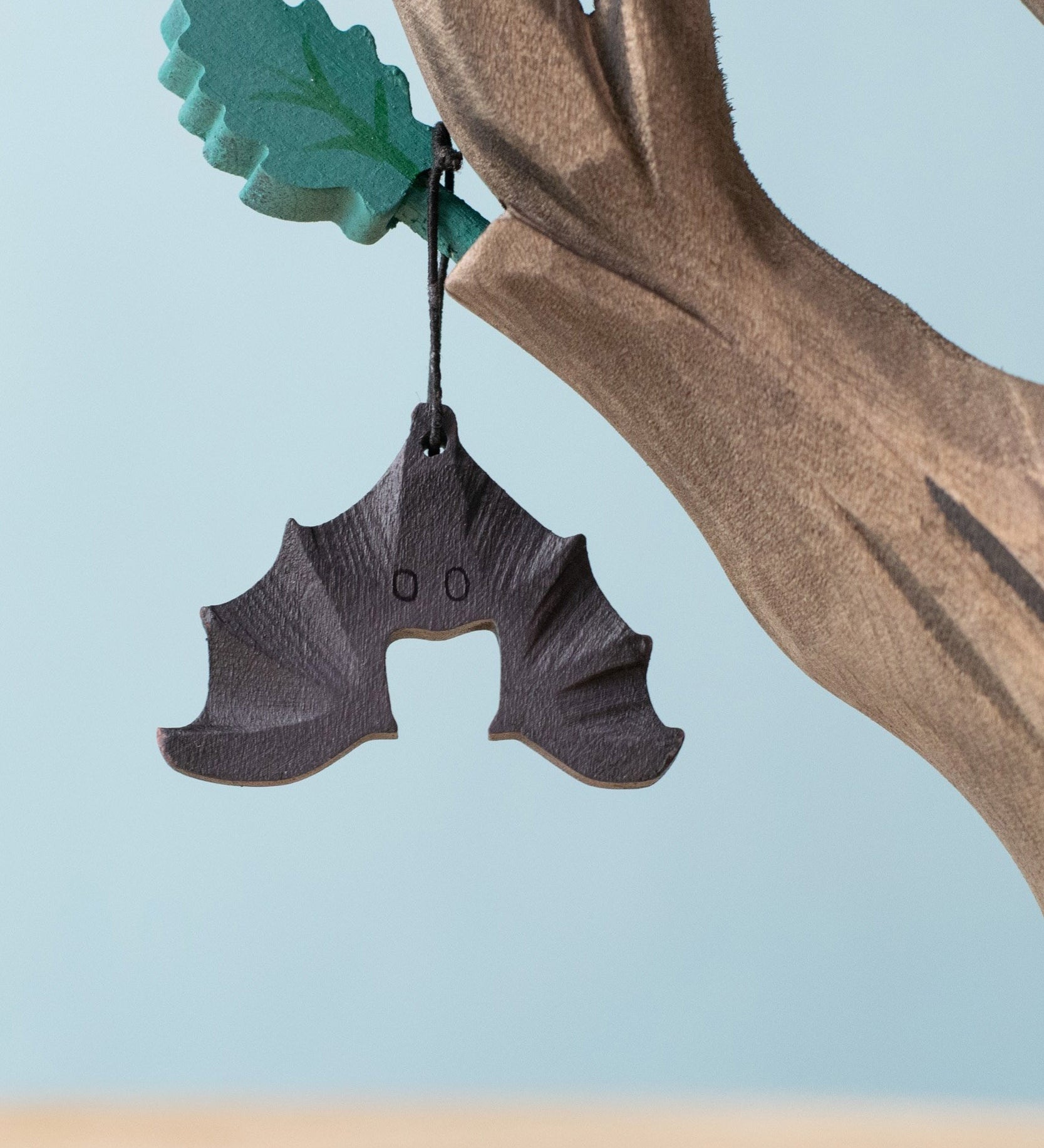 Bumbu handmade and hand painted wooden bat figure available at Babipur with its wings spread out. Features a small hole with a thread looping through for the bat to hang off a tree