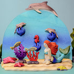 Bumbu wooden Mermaid toy figure posed in an aquatic ocean scene with Bumbu fish