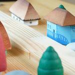 Close up of the Bumbu eco-friendly Oltenia miniature toy house on a wooden table next to a grapat mandala tree