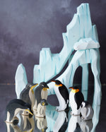 Bumbu Wooden Penguin Chick with male and female emperor penguins with the icy cliffs seen in the background