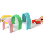 Pieces of the Bumbu wooden pastel arches lined up in a tunnel shape for a little red car toy