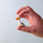 Bumbu Toys Wooden Pelican Chick, being held in an adult's hand.