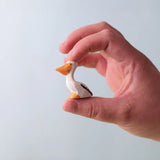Bumbu Toys Wooden Pelican Chick, being held in an adult's hand.