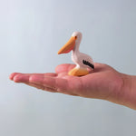 Bumbu Toys Wooden Pelican, being held in an adult's hand.
