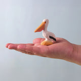 Bumbu Toys Wooden Pelican, being held in an adult's hand.