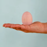 Adult hand holding the Bumbu handcrafted festive pink egg decorative figure showing size