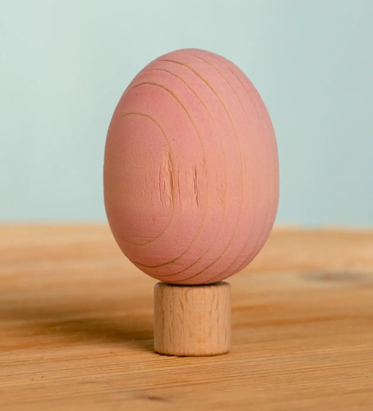 Bumbu handcrafted wooden pink egg figure standing on wooden base for Grimms celebration ring