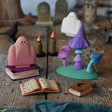 A pink Bumbu ghost placed in a small world play scene next to the Bumbu Wooden Enchanted Mushrooms Set. These expertly hand crafted items are part of a large range of wooden toys available here at Babipur. 