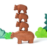 Bumbu sustainably sourced wooden bear toys stacked in a tower in front of some green wooden tree toys on a white background