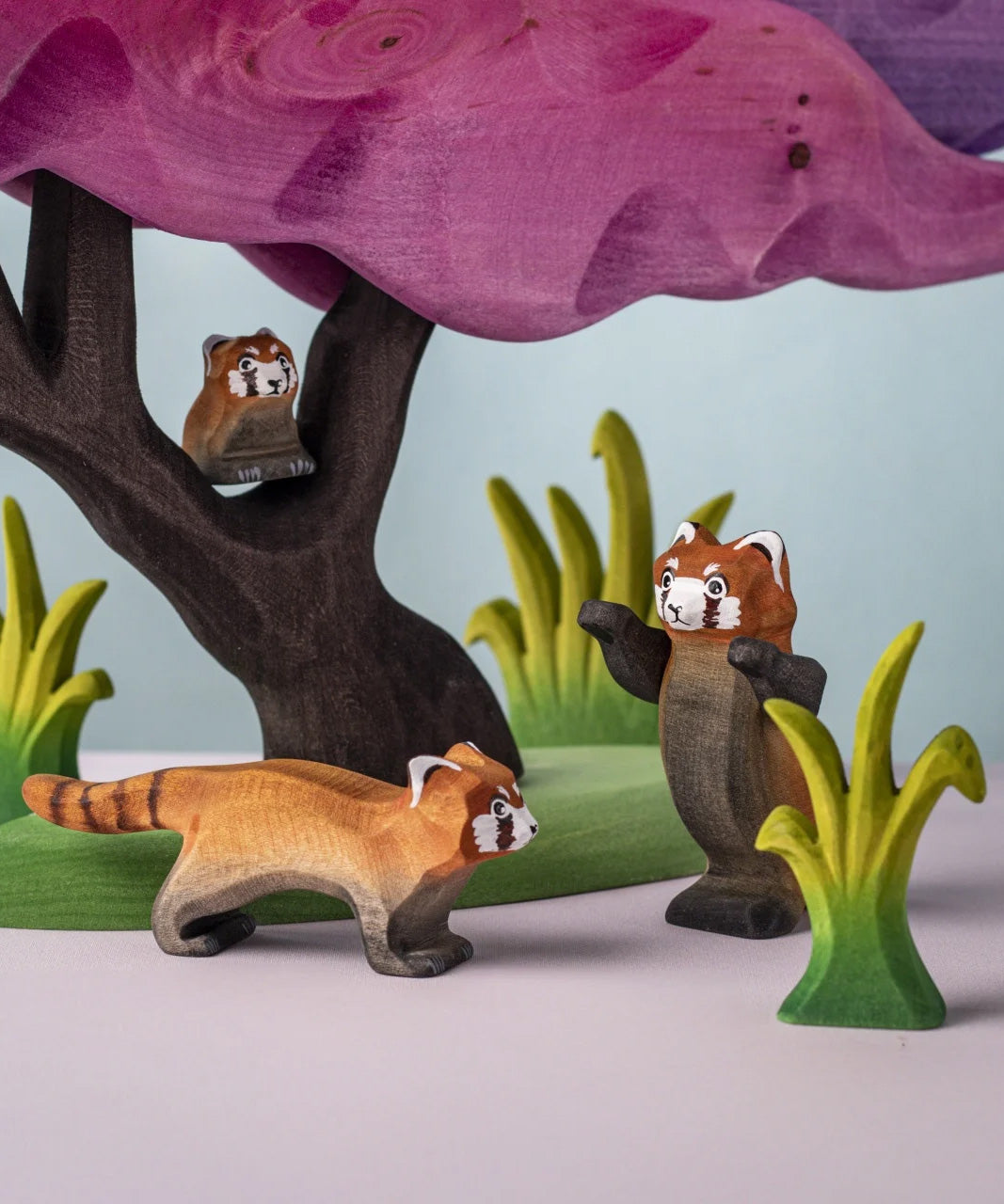 A family of the Bumbu red panda wooden figures in a nature play scene