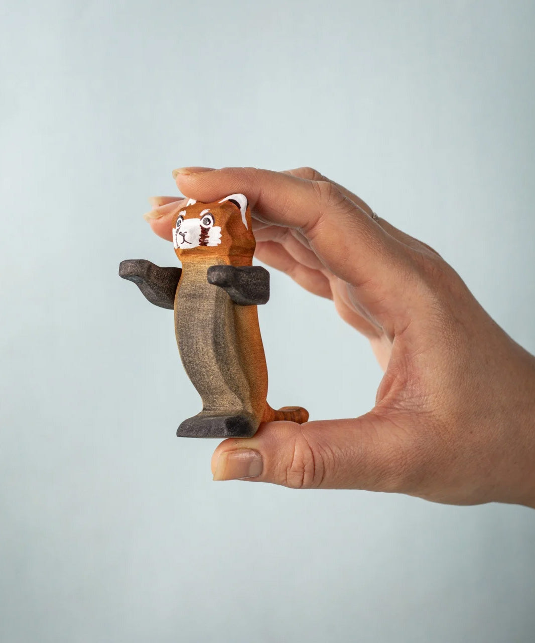  A hand holding the Bumbu playful red panda figure 