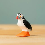 Bumbu Toys puffin handmade wooden toy figure placed on a wooden surface. 